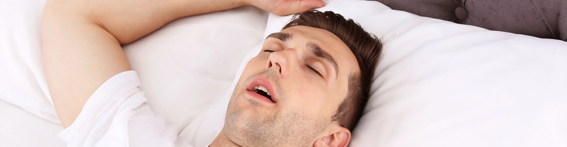 man sleeping on his back in bed.